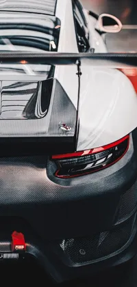 This phone live wallpaper features a striking Porsche sports car parked in a showroom, with a photorealistic, close-up shot taken from behind
