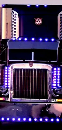 This phone live wallpaper showcases a close-up of a powerful semi-truck with its lights illuminated, inspired by iconic vehicles featured in popular movies
