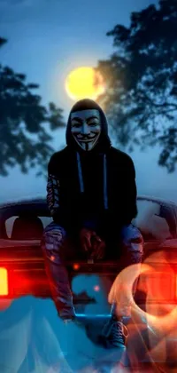 This vivid phone live wallpaper presents an enigmatic male silhouette sporting an anonymous mask and sitting atop a moving car against the backdrop of a starry night illuminated by a full moon