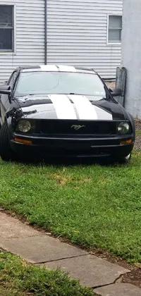 This phone live wallpaper showcases a black sports car parked in front of a house