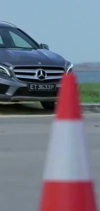 This live wallpaper features a Mercedes Benz car driving past a traffic cone on a road