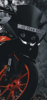 This engaging phone live wallpaper showcases an impressive black and orange motorcycle parked amongst vibrant woodland scenery