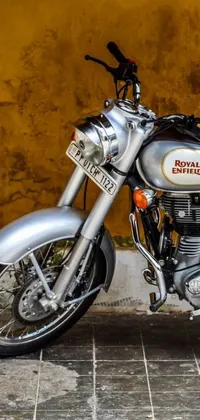 Get ready to add a touch of realism to your phone with this stunning live wallpaper featuring a classic silver motorcycle parked in front of a vibrant yellow wall