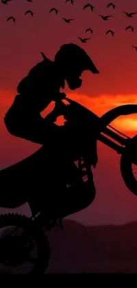 Rev up your phone's screen with this exciting live wallpaper featuring a dirt bike rider tearing it up at sunset