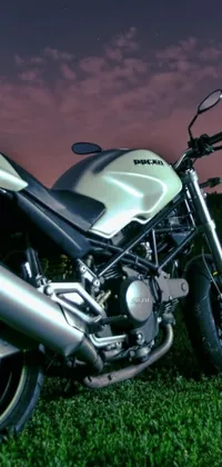 This phone live wallpaper showcases a powerful motorcycle parked on a lush green field