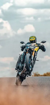 This phone live wallpaper features a hyper-realistic image of a biker cruising on the back of a motorcycle down a winding road