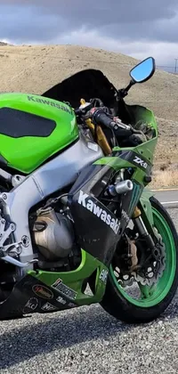This phone live wallpaper showcases a stunning green and black motorcycle, parked by the side of the road