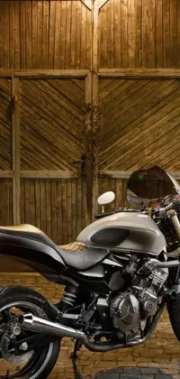 This live wallpaper for your phone features a stunning motorcycle parked in front of an old barn, with a dynamic, golden-dappled lighting effect that adds movement and energy to the scene