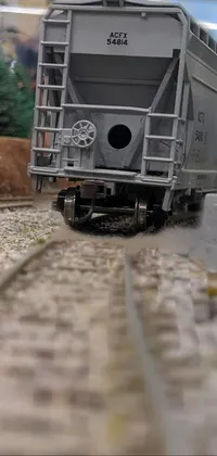 This train live wallpaper features a high detailed and photorealistic image of a train moving down tracks next to a brick building