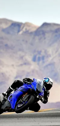 Get ready for an exciting ride with this amazing phone live wallpaper! Experience the thrill as a rider cruises on the back of a blue motorcycle on a race track located in the Mojave desert, leaving a cloud of dust behind