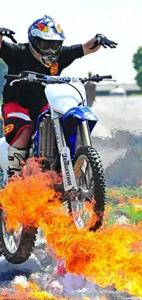 This live phone wallpaper showcases a dynamic portrait of a dirt bike rider in midair, surrounded by flames and fiery explosions