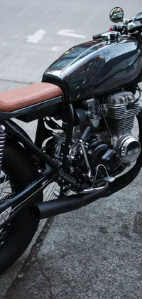 Looking for a high-quality motorcycle wallpaper for your phone? Check out this black motorcycle parked on the side of the road, with a 1960s cafe racer style