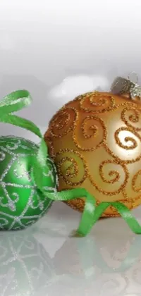 This live wallpaper showcases a stunning pair of ornaments in green and gold, sitting on a table