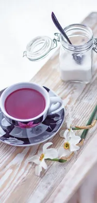 This live wallpaper features a cup of tea on a wooden table, with a colorful painting in the background