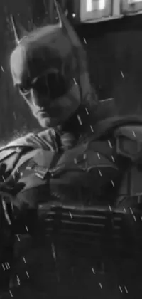 This phone live wallpaper features a captivating black and white photo of Batman standing stoically in the rain, exuding strength and determination