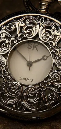 This phone live wallpaper depicts a steampunk pocket watch on a chain with intricate baroque patterns on its face