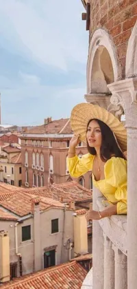 This phone live wallpaper depicts an Asian woman standing atop a balcony next to a tall building in Venice