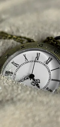 Enhance your phone's wallpaper collection with this beautiful close-up live wallpaper of a vintage pocket watch stuck in sand