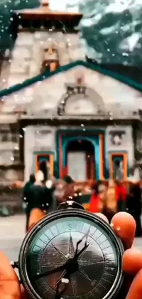 This captivating phone live wallpaper features a stunning, intricate building and a compass being held up in the forefront