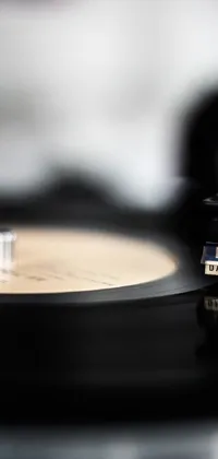This phone live wallpaper features a vintage record player's turntable and a grooving vinyl record with a clear label