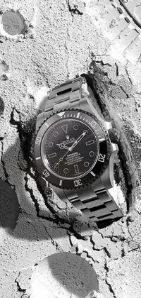 Upgrade your phone's wallpaper with a stunning black and white image of a Rolex watch abandoned in the sand by Photographer Doug Wildey
