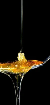 Introducing a stunning live wallpaper for your phone featuring a glistening spoon with honey drizzling over it