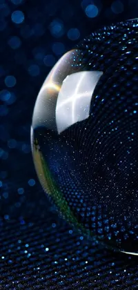 This live phone wallpaper captures a glass ball resting on a blue surface in incredible detail