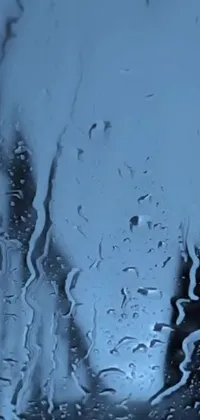 This phone live wallpaper features a rain-soaked window with droplets running down in an artistic video art piece