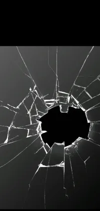 This phone live wallpaper features a striking design of a broken glass window with a hole in it set against a solid black background