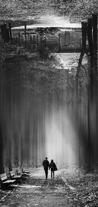 This forest live wallpaper depicts two individuals strolling through the woods in an artistic black and white photograph