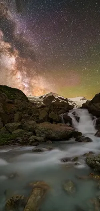 This stunning phone live wallpaper boasts a serene and peaceful body of water surrounded by rocks under a mesmerizing night sky