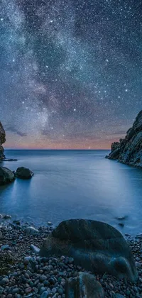 Transform your phone with a stunning live wallpaper featuring a rocky beach under a twinkling night sky filled with stars