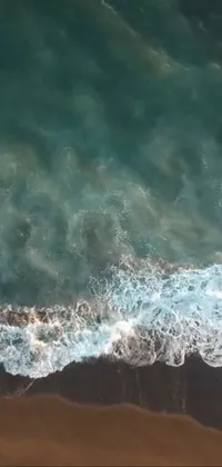 Experience the thrill of surfing with this mesmerizing phone live wallpaper, featuring drone footage of a black-sand beach and a surfer riding the waves on a white board