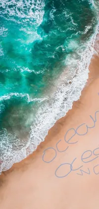 This stunning live wallpaper features an aerial shot of a message written on a sandy beach next to the ocean