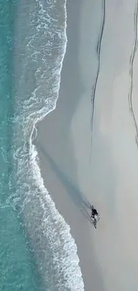 This live phone wallpaper showcases an impressive scene of a surfer riding a board on a breathtaking sandy beach