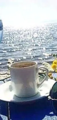 This stunning phone live wallpaper features a cup of coffee and a glass of water sitting on a wooden table