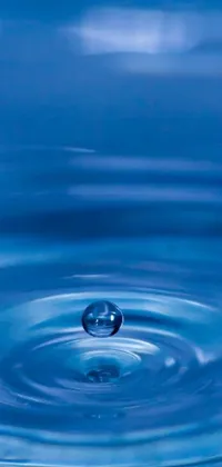 This phone live wallpaper features a calming and serene close-up of a water droplet in a body of water