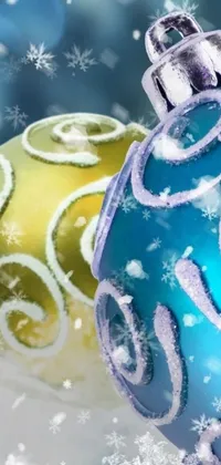 This phone live wallpaper features a stunning representation of two Christmas ornaments amidst a snowy backdrop