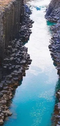 This live wallpaper features a serene hyperrealistic depiction of a body of water surrounded by rocks and concrete pillars, with canal boats passing by