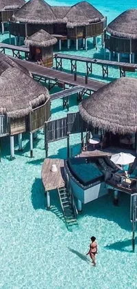 This phone live wallpaper features a stunning luxury lifestyle scene of thatched huts floating on water viewed from a helicopter perspective