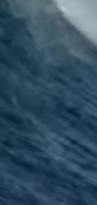 This live wallpaper for your phone depicts a thrilling scene of a surfer riding a giant wave