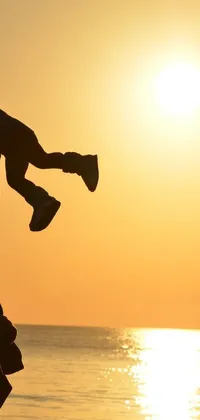 This stunning phone live wallpaper features a heartwarming image of a man raising a child up in the air against a gorgeous sunset backdrop