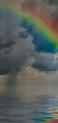 This phone live wallpaper features a breathtaking image of a rainbow over a body of water