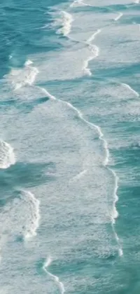 This phone live wallpaper showcases a surfer catching a big wave on a beach covered in teal water