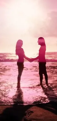 This phone live wallpaper depicts a beautiful beach scene where a man and a woman are holding hands under a pink-shadowed sky