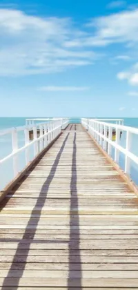 This stunning phone live wallpaper features a wooden pier stretching out into the sparkling blue ocean, surrounded by white sandy beaches and clear skies with fluffy clouds