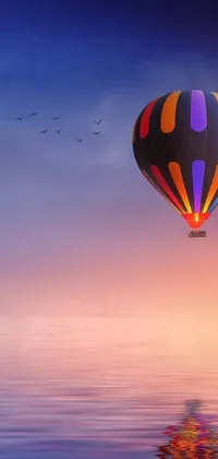 This stunning phone live wallpaper features a colorful hot air balloon flying over a misty body of water at sunrise