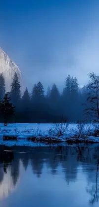 This live wallpaper features a picturesque winter landscape- a serene body of water nestled amidst snow-capped mountains, surrounded by mystical blue fog