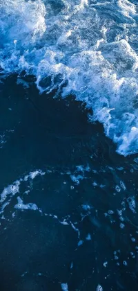 This phone live wallpaper features an incredible digital art of a man riding a wave on his surfboard in the deep blue sea