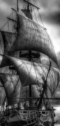 This black and white live wallpaper features an intricate tall ship sailing under a dark cloudy sky in the midst of crashing waves